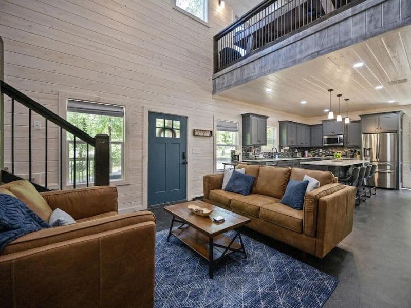 Open concept living space in a large Broken Bow cabin rental, with high ceilings, modern kitchen, and comfortable lounge area.