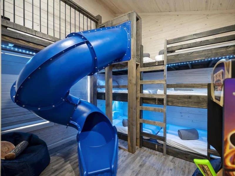 Children's bedroom in a Broken Bow group cabin rental featuring bunk beds with a blue slide coming down from the top bunk.