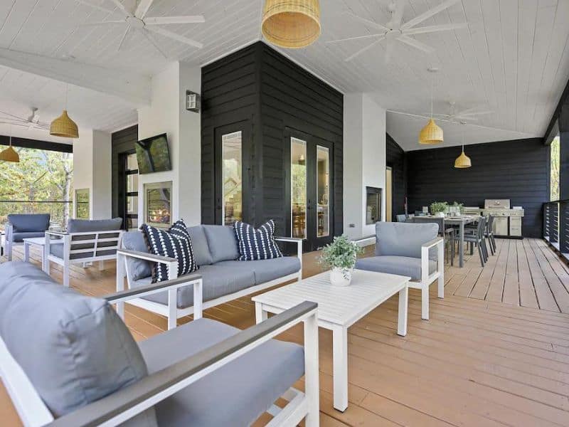 Spacious covered patio area with modern outdoor furniture and a kitchenette in 'Casa Arbol,' a large cabin rental in Broken Bow, OK.