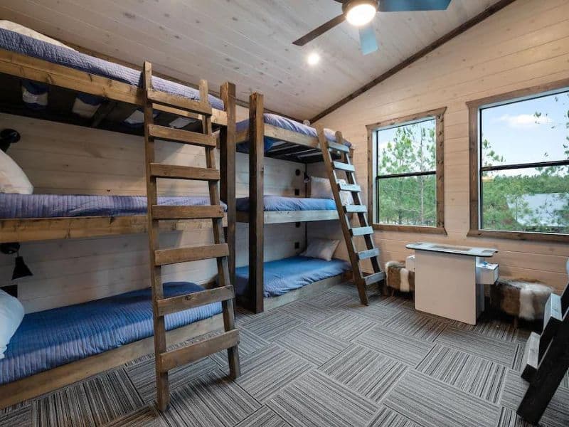 Bunk room with four wooden bunk beds fitted with blue linens in a 5-bedroom Broken Bow cabin rental.