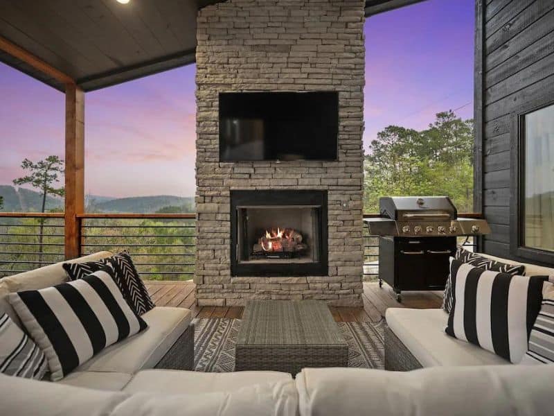 Cozy outdoor seating area with a fireplace and striped pillows at 'Hell Of A View,' a luxurious Broken Bow large cabin rental.