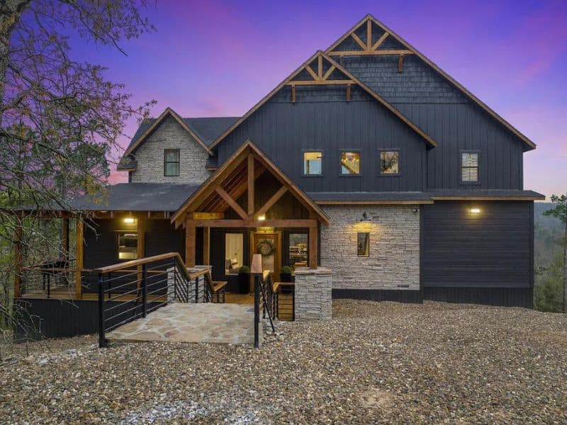 Exterior shot of 'Hell Of A View' at dusk, featuring the cabin's impressive architecture and outdoor lighting. Broken Bow, OK.