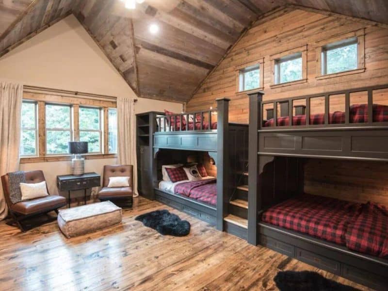 A bunk room in a Broken Bow cabin rental featuring four cozy beds with red plaid bedding and wooden interior details.