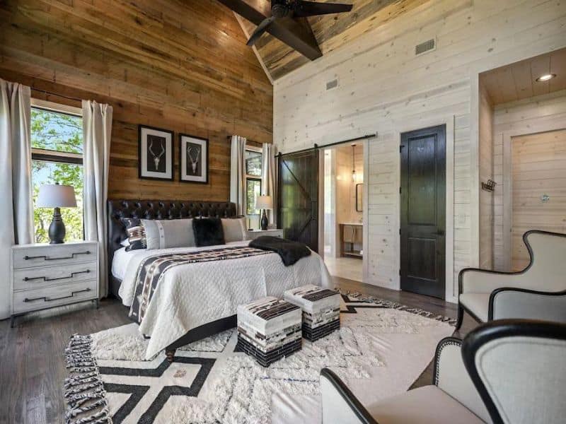 Elegant master bedroom in a Broken Bow cabin rental with a mix of natural wood textures, a plush king-sized bed, and a sleek, modern decor.