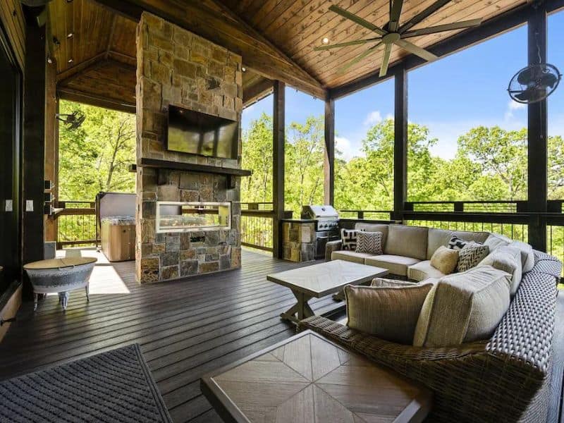 Spacious porch with an outdoor fireplace and comfortable seating area at Modern Moose Lodge in Broken Bow, OK.