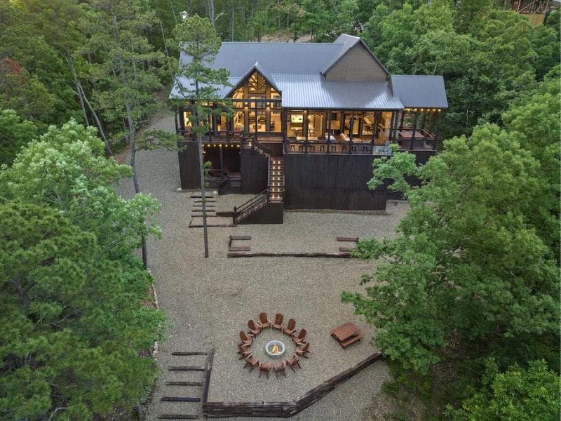 Aerial view of Modern Moose Lodge nestled among trees, a Broken Bow large luxury cabin rental, with an outdoor fire pit and multiple levels of decking.