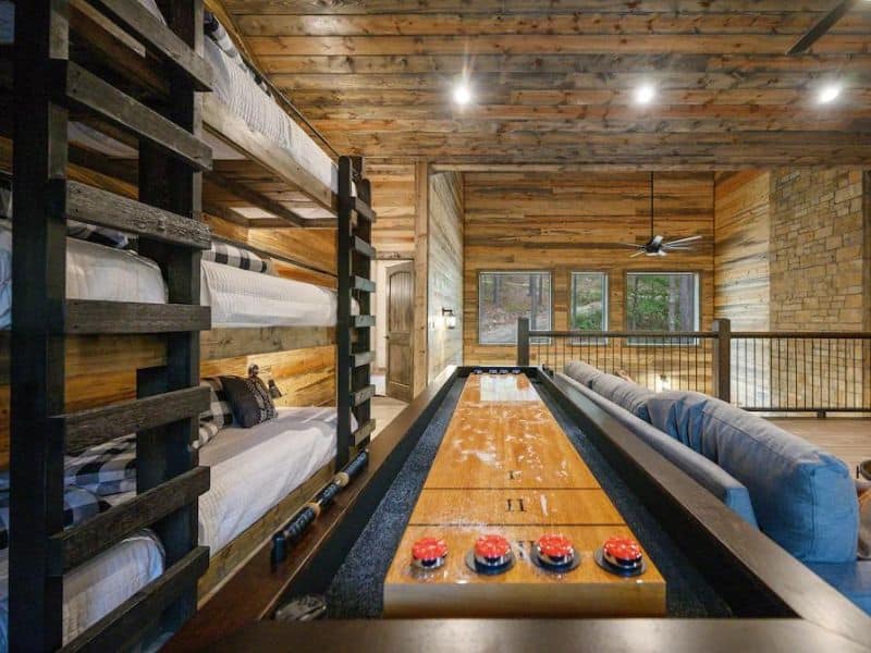 Game area with a shuffleboard table and tiered bunk beds in a Broken Bow large cabin rental.