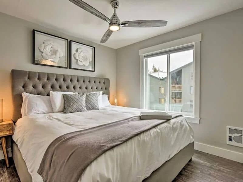 Elegant bedroom with a tufted headboard and large window in a ski in ski out Park City vacation rental.