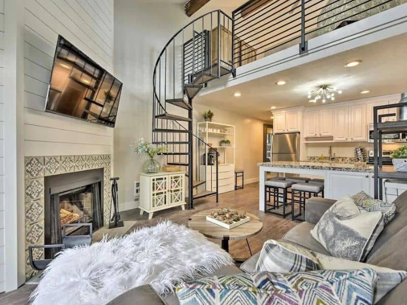 Chic living space with a spiral staircase leading to a loft, featuring a tiled fireplace in a Park City ski in ski out rental.