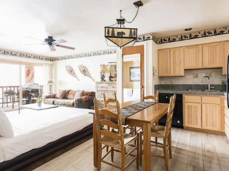 Open-plan dining and living space featuring a wooden dining table and kitchenette in a ski in ski out rental in Park City.