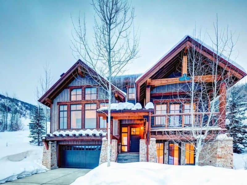 Exterior of Silver Star vacation rental, Park City, with grand, chalet-style architecture and large windows, wooden beams, and a snow-covered landscape.