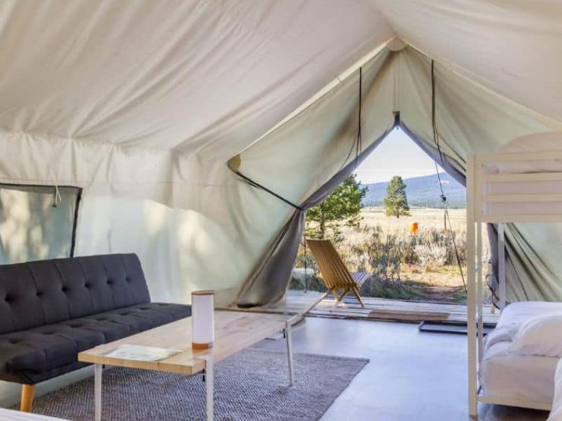 Glamping tent interior at Tammah Glamping near Yellowstone, with open canvas revealing the natural landscape.