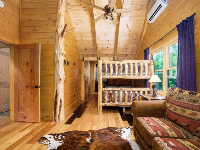 Set of queen bunk beds with leather couch and cowhide rug in Hocking Hills cabin