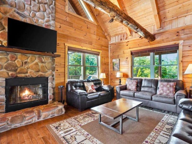 Living area in wood cabin with leather couches and fireplace