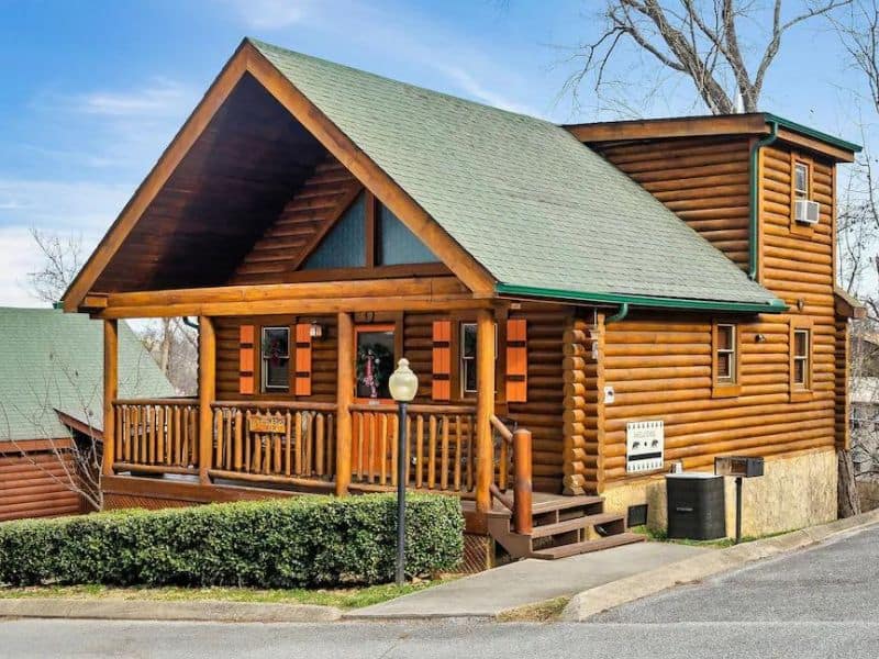 Exterior of Pigeon Forge log cabin rental, with pitched roof, front porch and orange detailing.