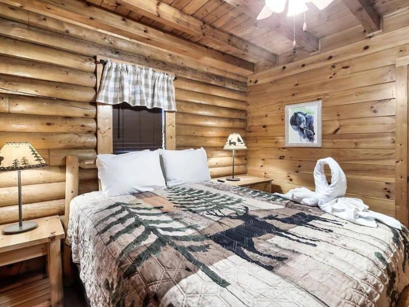 Bedroom of Pigeon Forge vacation cabin, with log siding, quilted bedding, and rustic decor.
