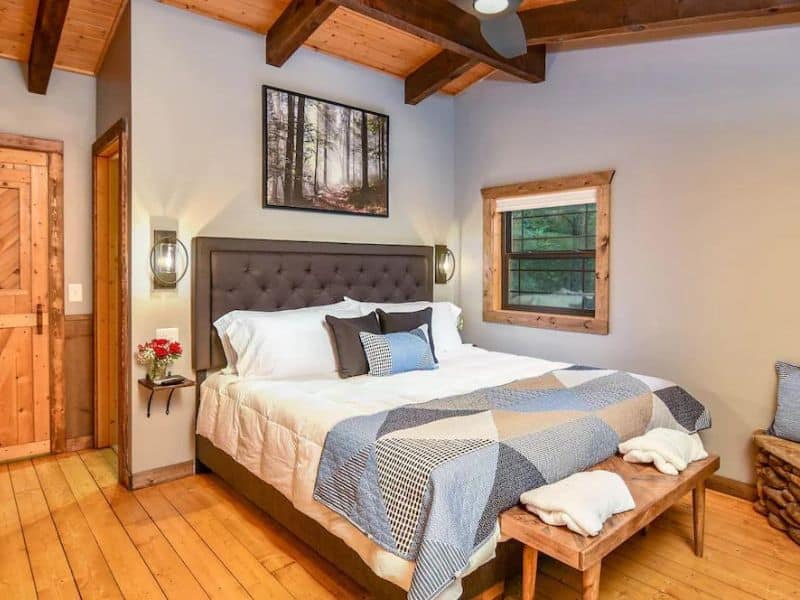 Bedroom of Pigeon Forge vacation cabin, with exposed wooden beam ceiling, quilted bedding, and rustic detailing.