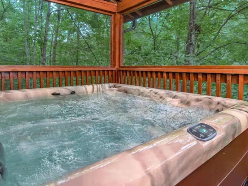 Porch hot tub of Pigeon Forge rental cabin, looking out to a forest view.