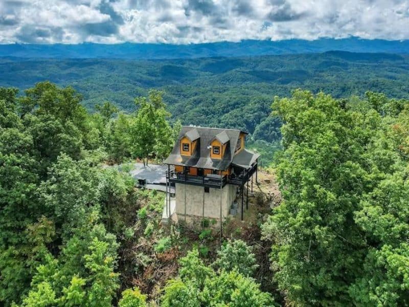 Vacation cabin in Pigeon Forge, cantilevered out on a mountain top with green forest surrounding.