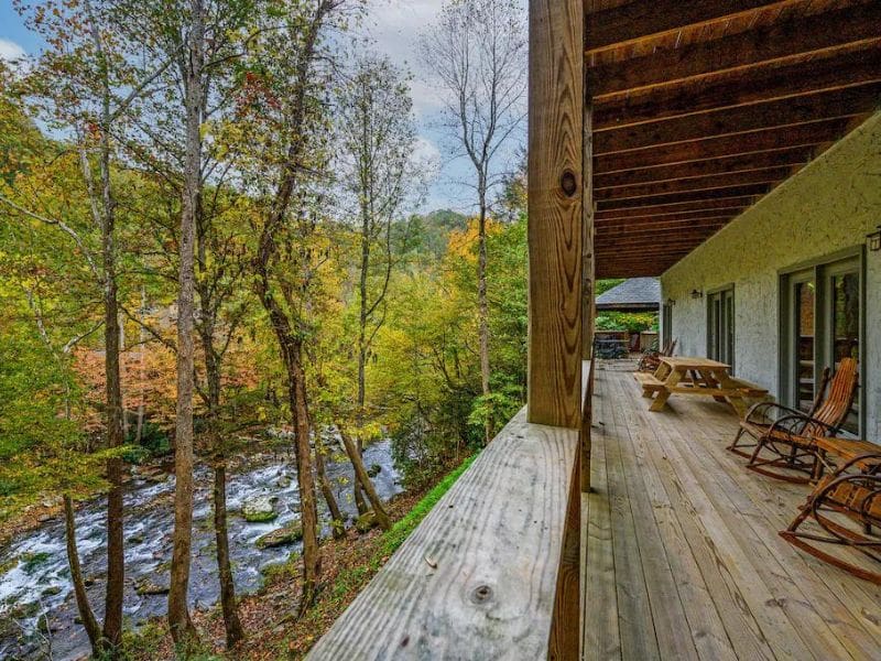 Large wooden deck with rocking chairs overlooking Little Pigeon River at Pigeon Forge Cabin Rental