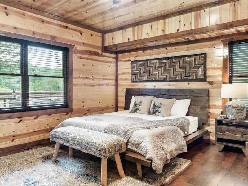 Bedroom with plush decor and neutral tones, wood paneling and views of the forest, of Pigeon Forge rental property.
