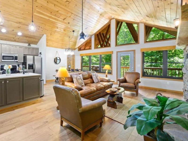 Living area of Pigeon Forge vacation home, with light wooden accents, angled ceiling, and forest views
