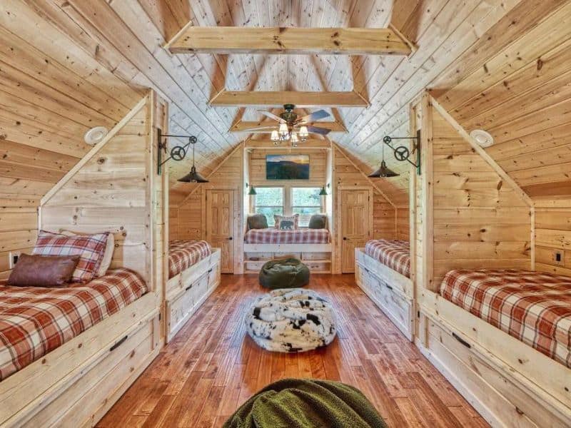 Interior shot of wooden Pigeon Forge cabin, of 5 attic bunks with bean bag chairs and rustic decor.