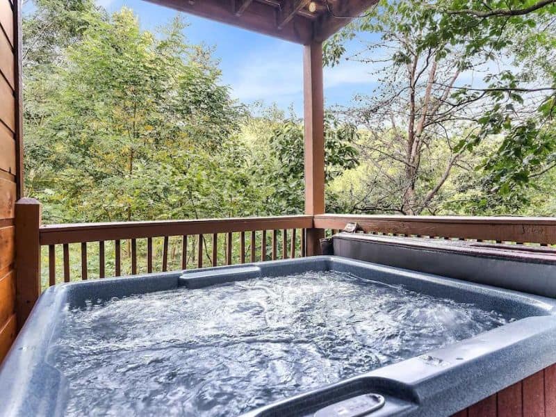 Balcony Jacuzzi at Pigeon Forge cabin, with views of mountains and forest.