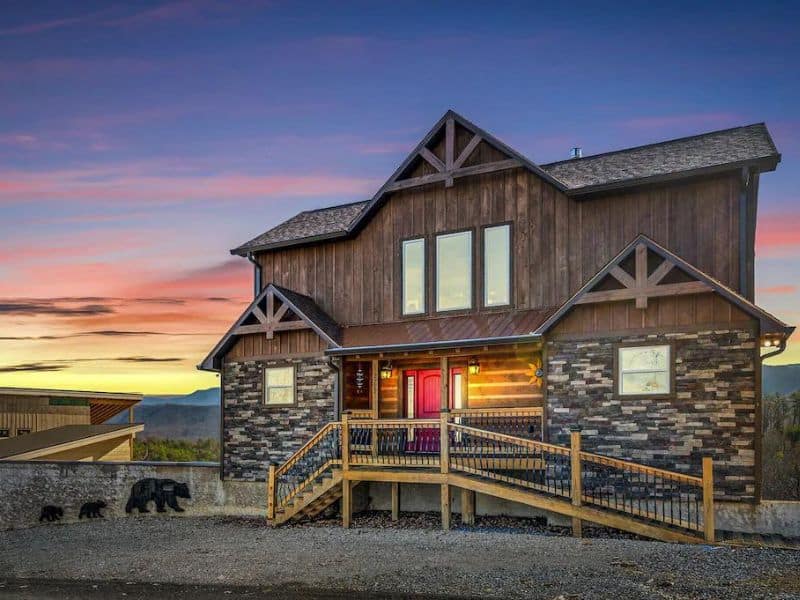 Exterior of Pigeon Forge vacation cabin, with stone and wood accents, with mountain views at sunset.