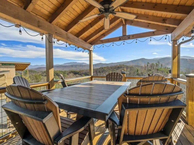 Outdoor covered dining area on balcony with mountain views, and cafe lights in Pigeon Forge vacation home.