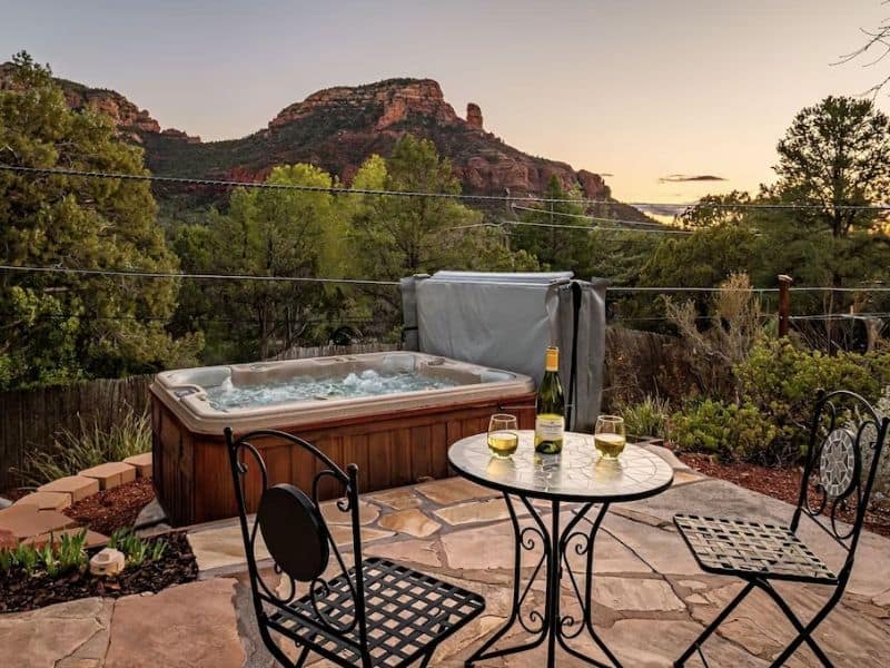 Outside table for two with wine glasses and hot tub with red rock views at home rental in Sedona