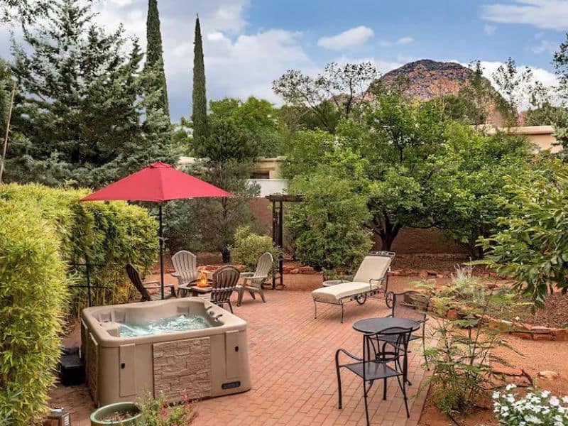 Backyard of popular Sedona airbnb with hot tub, patio seating, and view of Mount Thunder in the background