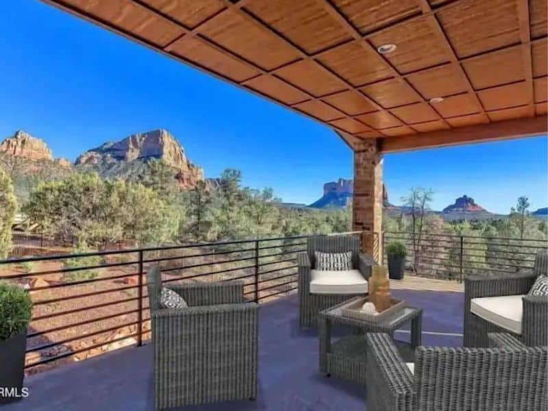Outdoor covered living area on the balcony of Sedona rental, featuring views of rock formations, and trees.
