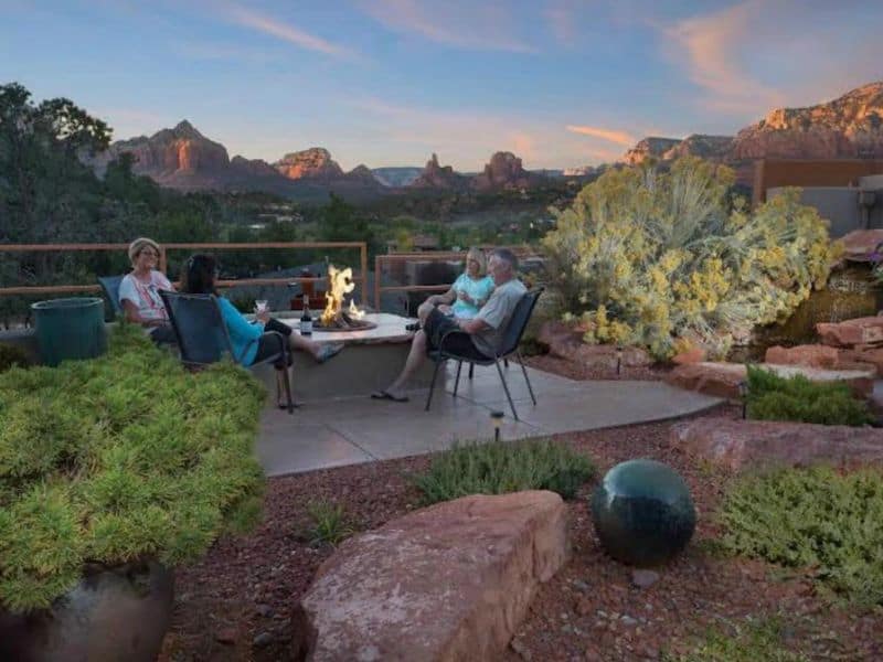 People sitting around an outdoor fire pit at dusk in Sedona, AZ