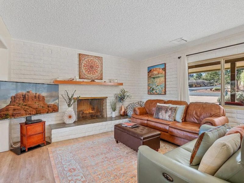 Living room of Sedona vacation home with fireplace, whitewashed walls, and colorful bohemian accents.