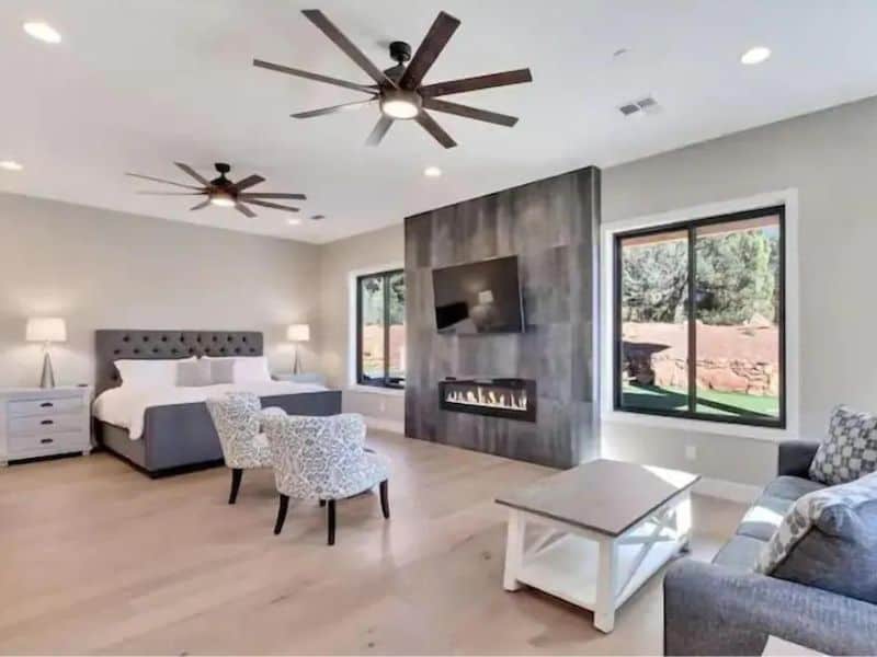 Master bedroom in Sedona rental home with fireplace, living area, and views of red rock formations.