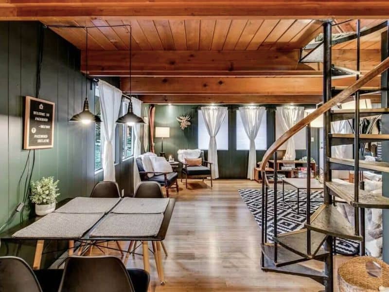 Open living area in Mt Rainier cabin rental with spiral staircase, small dining table and lots of windows
