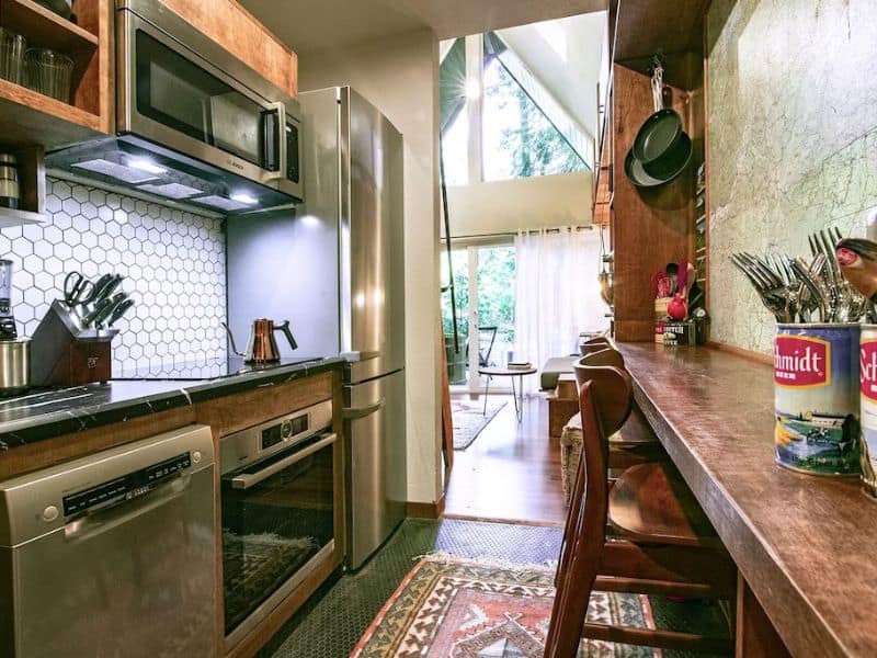 Vintage photo of a small kitchen in an A-frame cabin with stainless steel appliances and small breakfast bar