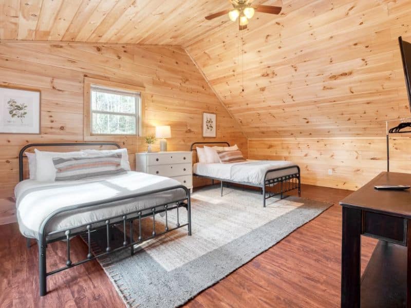 Bedroom in cabin with wood finishes and one queen bed and one twin bed