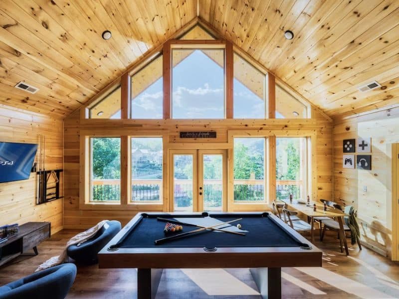 Game room in Gatlinburg vacation rental with pool table and large windows and vaulted ceilings allowing in ample light