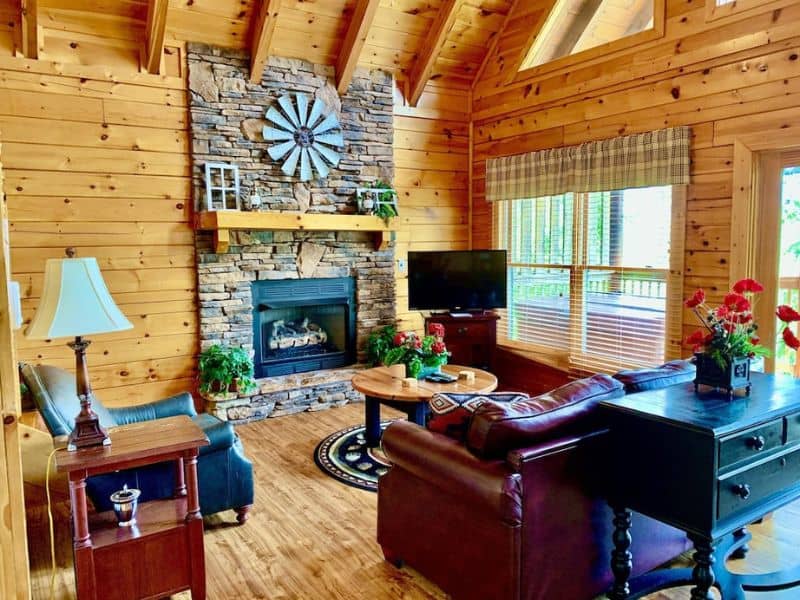 Living area in pet-friendly Gatlinburg cabin with stone fireplace, TV, and and leather couches.