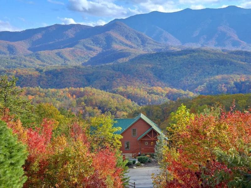 Wide angle view of wood cabin with green roof in the middle of the Great Smoky Mountains - part of a round up of the best pet-friendly Gatlinburg cabins