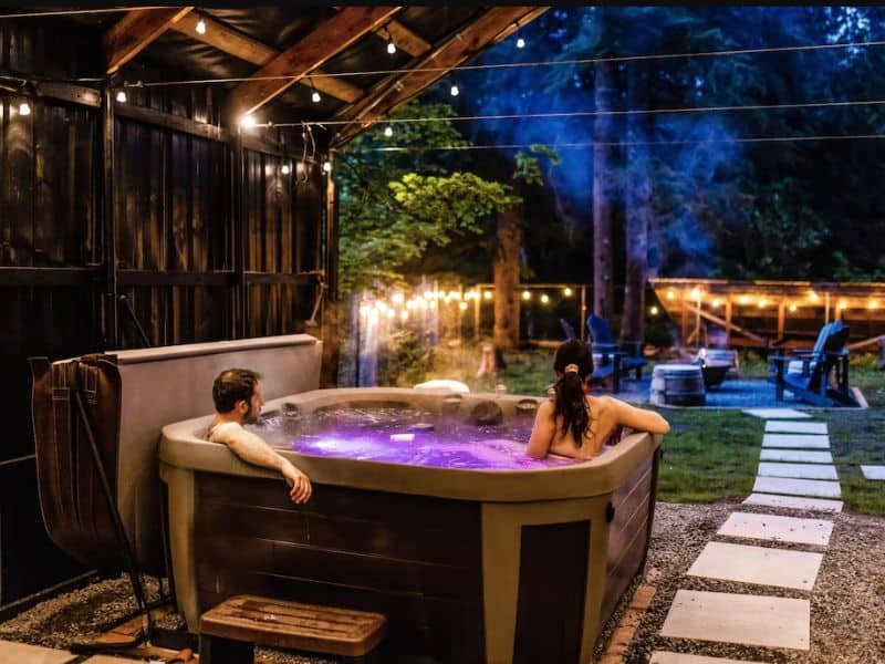 Mt Rainier cabin rental with covered hot tub facing backyard with string lights