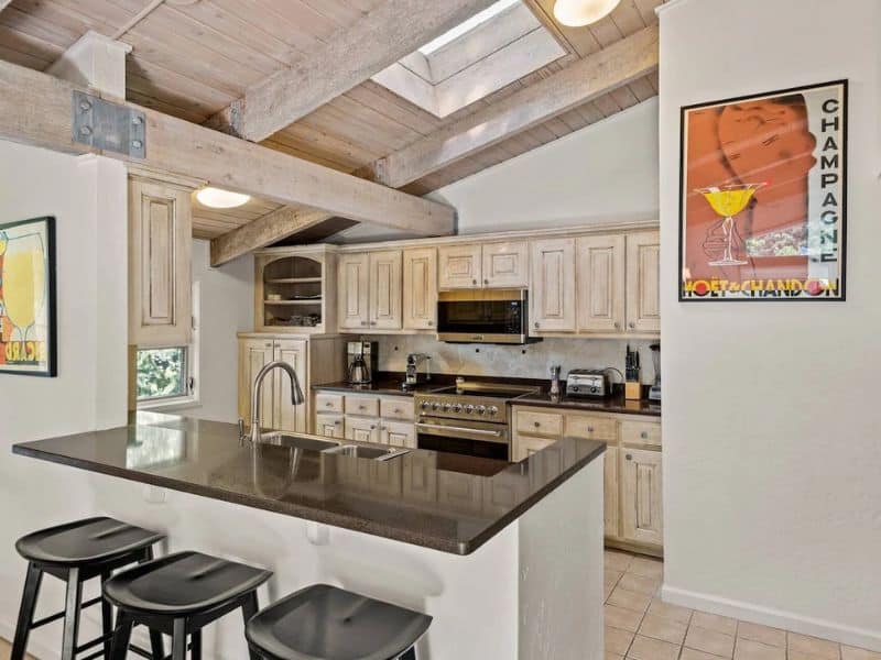 A kitchen with wood ceilings and bar stools in a rental in Aspen CO.