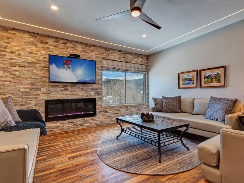 A living room with a stone fireplace and a flat screen tv in a Breckenridge ski in ski out condo.