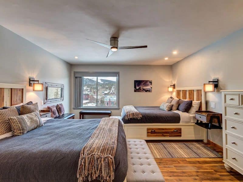 An updated bedroom with two beds and a ceiling fan at a Breckenridge Vrbo rental.