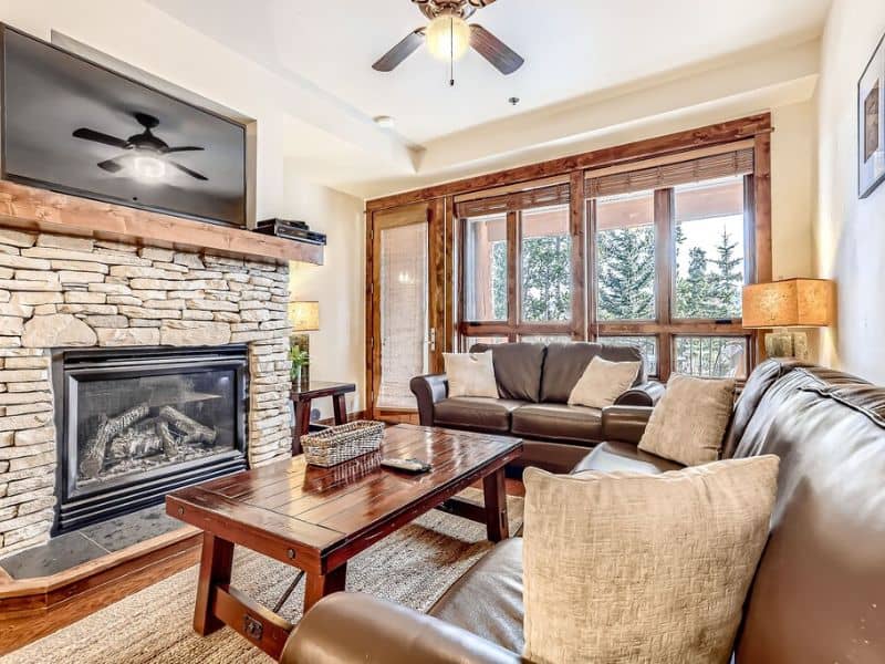 A modern living room with a stone fireplace and a flat screen tv at a ski in ski out condo in Breckenridge CO.