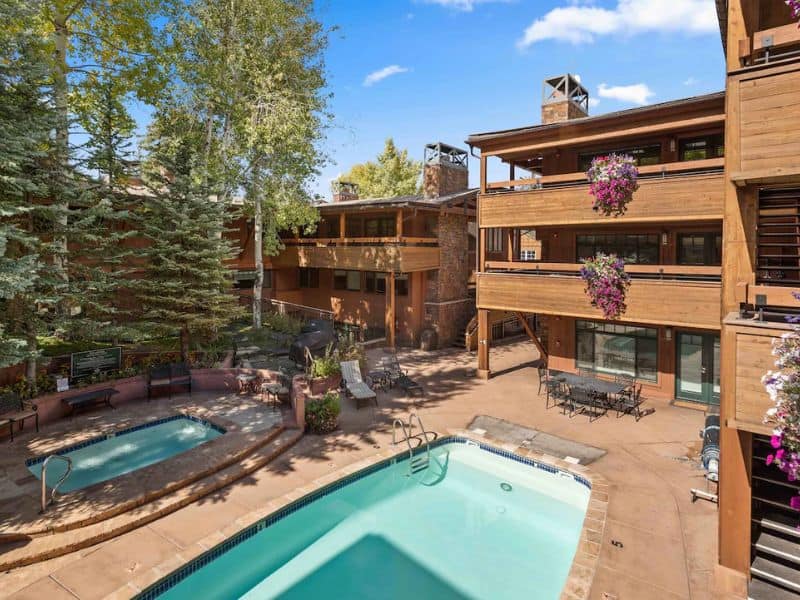 A ski-in, ski-out apartment complex in Aspen with a pool and trees.