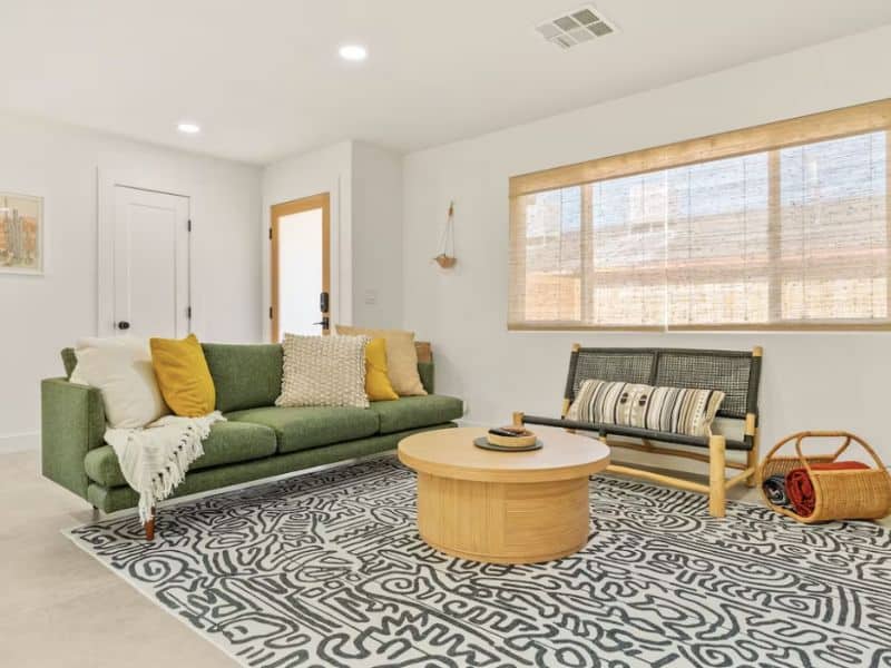 A living room in Joshua Tree Vrbo with a green couch, coffee table, and large area rug.