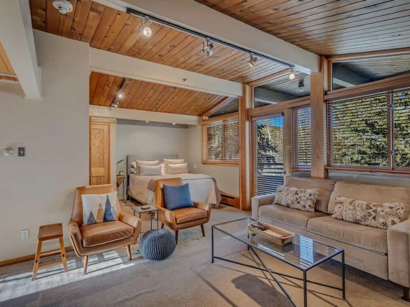 A living room with wood ceilings and a couch at a Vrbo listing in Aspen CO.